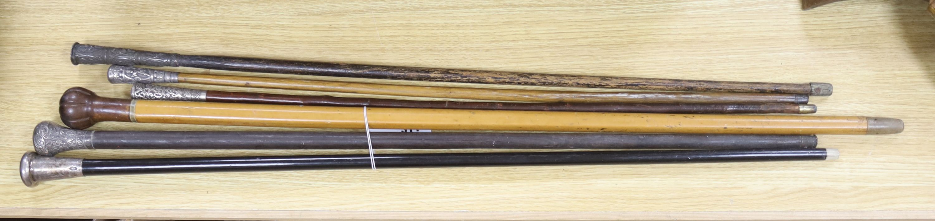 A set of six canes, one silver topped, four white metal and another